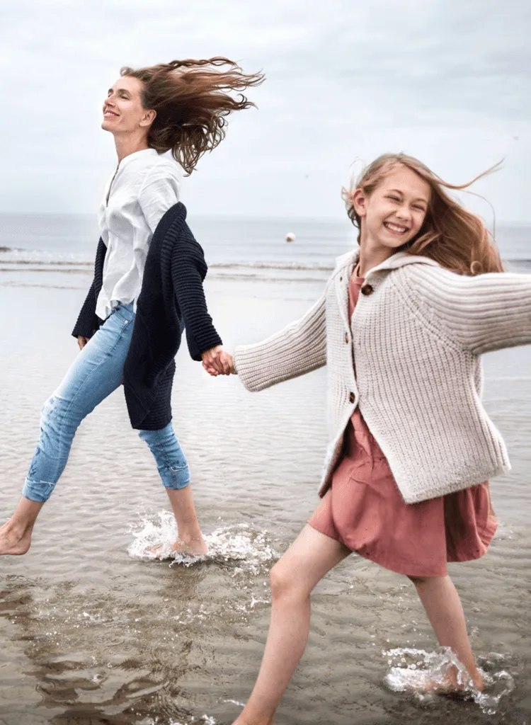 Moeder en dochter lopen hand in hand langs het strand
